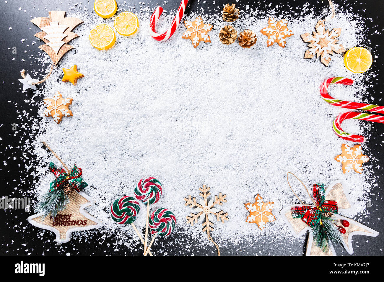 Fond de Noël avec des flocons de neige blanc, d'épices, des jouets, des bonbons au citron, et nouvel an vacances d'hiver. Décor cadre sur une table en bois noir Banque D'Images