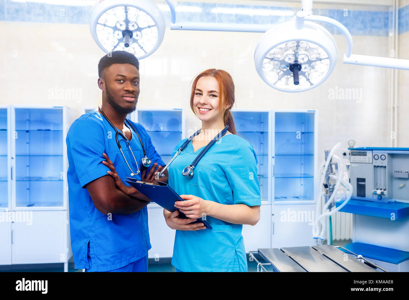 De l'équipe multiraciale de deux jeunes médecins dans un hôpital debout dans une chambre d'exploitation Banque D'Images