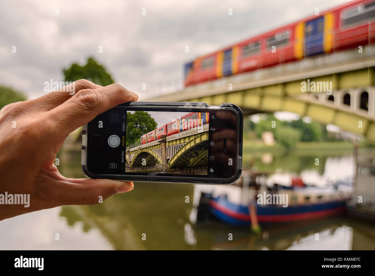 Un homme prenant des photos de Richmond pont de chemin de fer (structure classé Grade II) avec son iPhone SE, Londres Banque D'Images