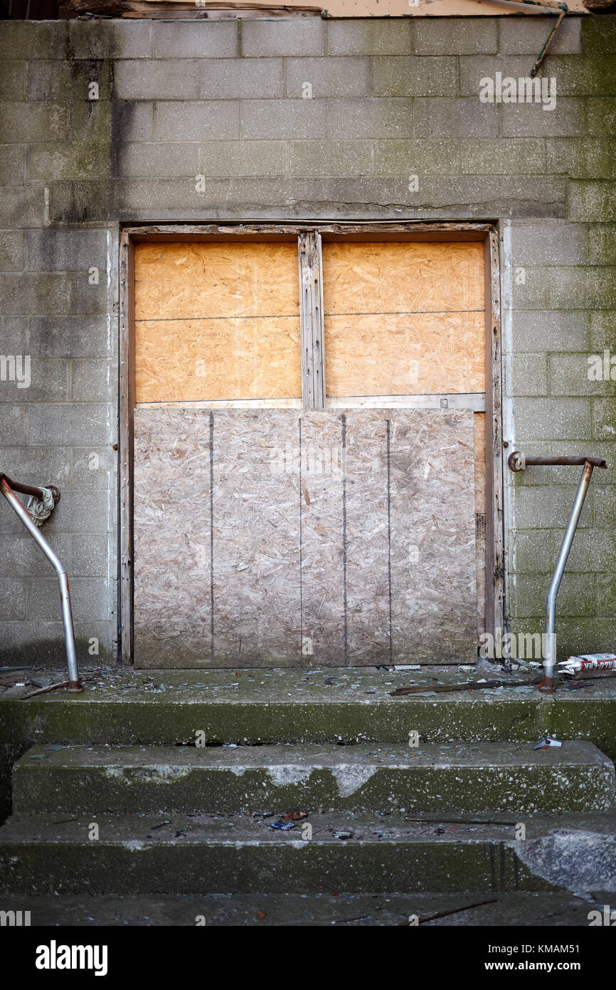 Vue de face de l'entrée d'un bâtiment abandonné ou non bloqué avec panneaux de bois pressé Banque D'Images