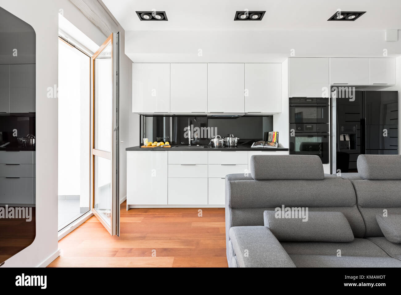 Salon moderne avec canapé, balcon et cuisine ouverte blanche Photo Stock -  Alamy