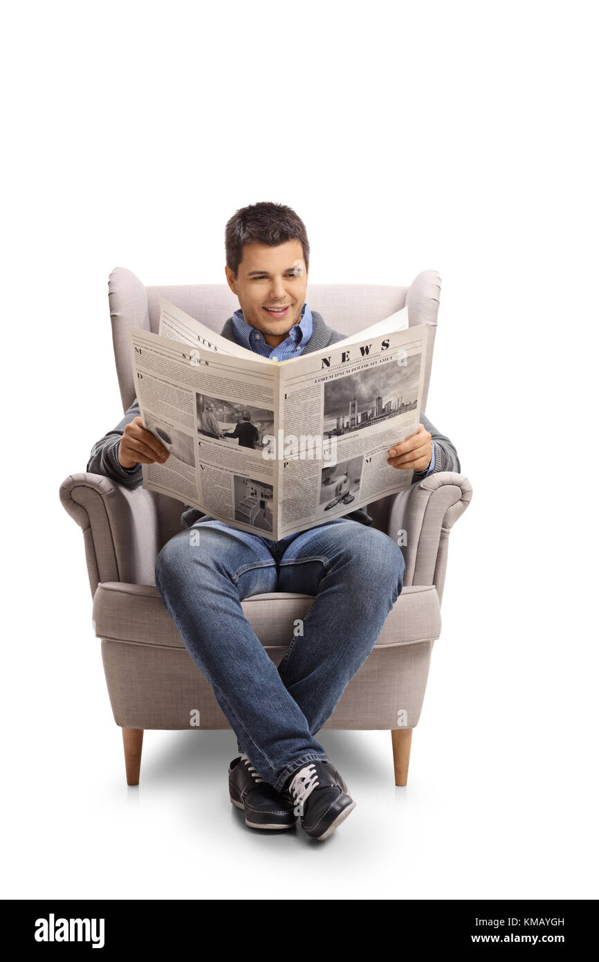 Jeune homme assis dans un fauteuil et lit un journal isolé sur fond blanc Banque D'Images