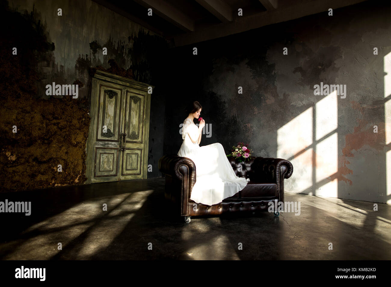 Belle robe de mariée assis sur une chaise à l'intérieur dans dark studio intérieur comme à la maison. Banque D'Images