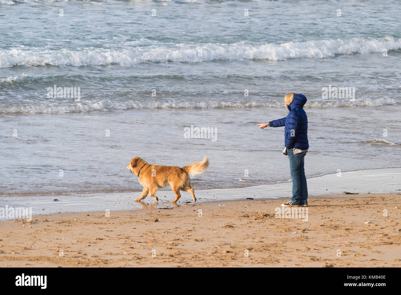 Propriétaire de chien - une femme et son chien sur la plage de Fistral Newquay Cornwall UK. Banque D'Images