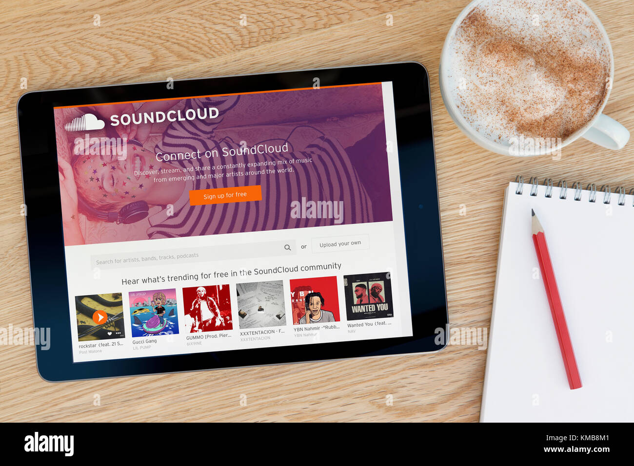 Le site web dispose d'un sur Soundcloud iPad tablet device qui repose sur une table en bois à côté d'un bloc-notes et un crayon et une tasse de café (seulement éditoriale Banque D'Images