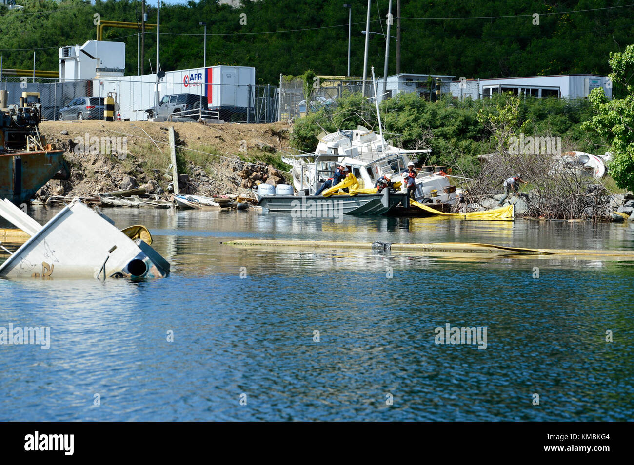 Les membres de la Garde côtière et un entrepreneur de l'Agence de protection de l'environnement supervisent le personnel de Resolve Marine Group, une société d'intervention sous contrat, alors qu'ils s'embarque d'un navire abandonné à Krum Bay dans le cadre de la mission et des opérations de la fonction de soutien d'urgence 10 à St. Thomas, le 2 décembre 2017. La perche est placée autour du navire avant d'extraire le carburant, l'huile ou tout produit potentiellement polluant qui peut être à bord d'un navire abandonné. Garde-côtes Banque D'Images