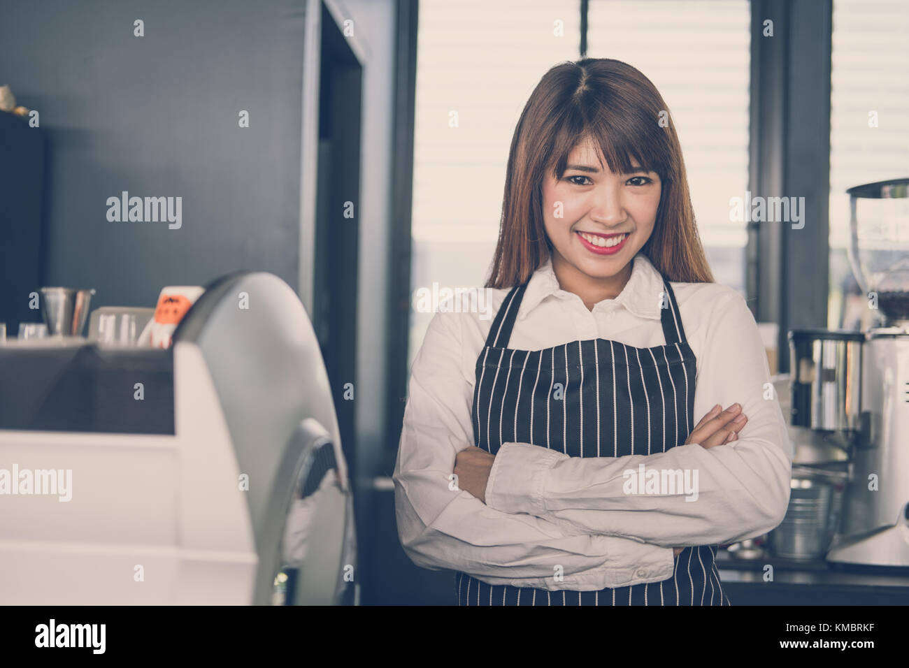 Small business owner standing at counter in coffee shop. asian female barista portant un tablier smiling at bar à café. food service, concept de restaurant. Banque D'Images