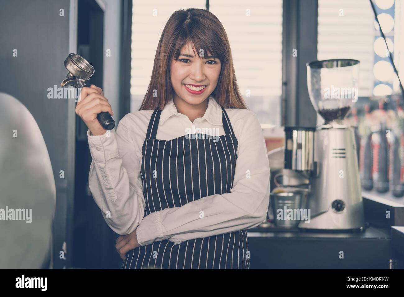 Small business owner standing at counter in coffee shop. asian female barista portant un tablier smiling at bar à café. food service, concept de restaurant. Banque D'Images