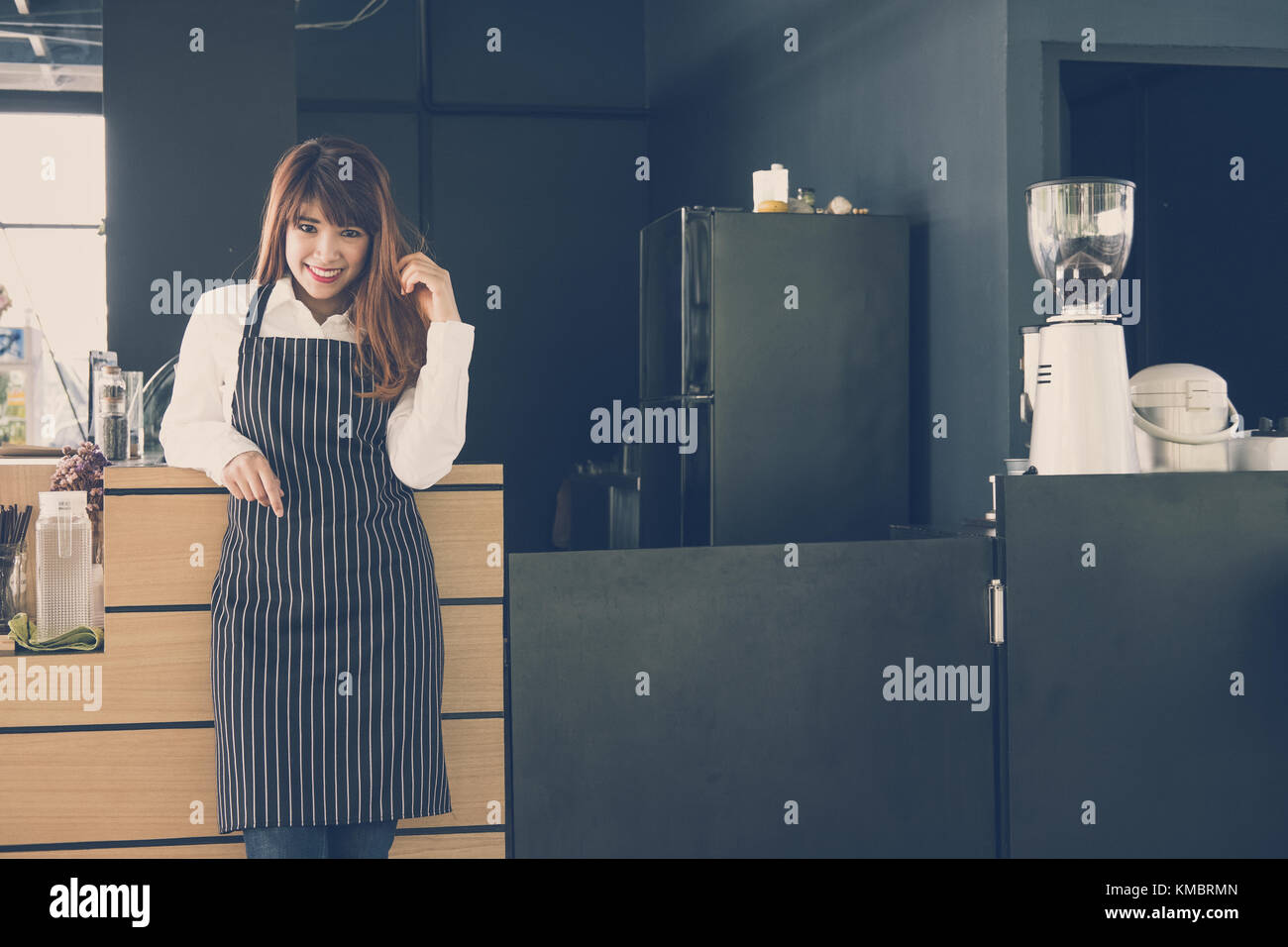 Small business owner standing at counter in coffee shop. asian female barista portant un tablier smiling at bar à café. food service, concept de restaurant. Banque D'Images