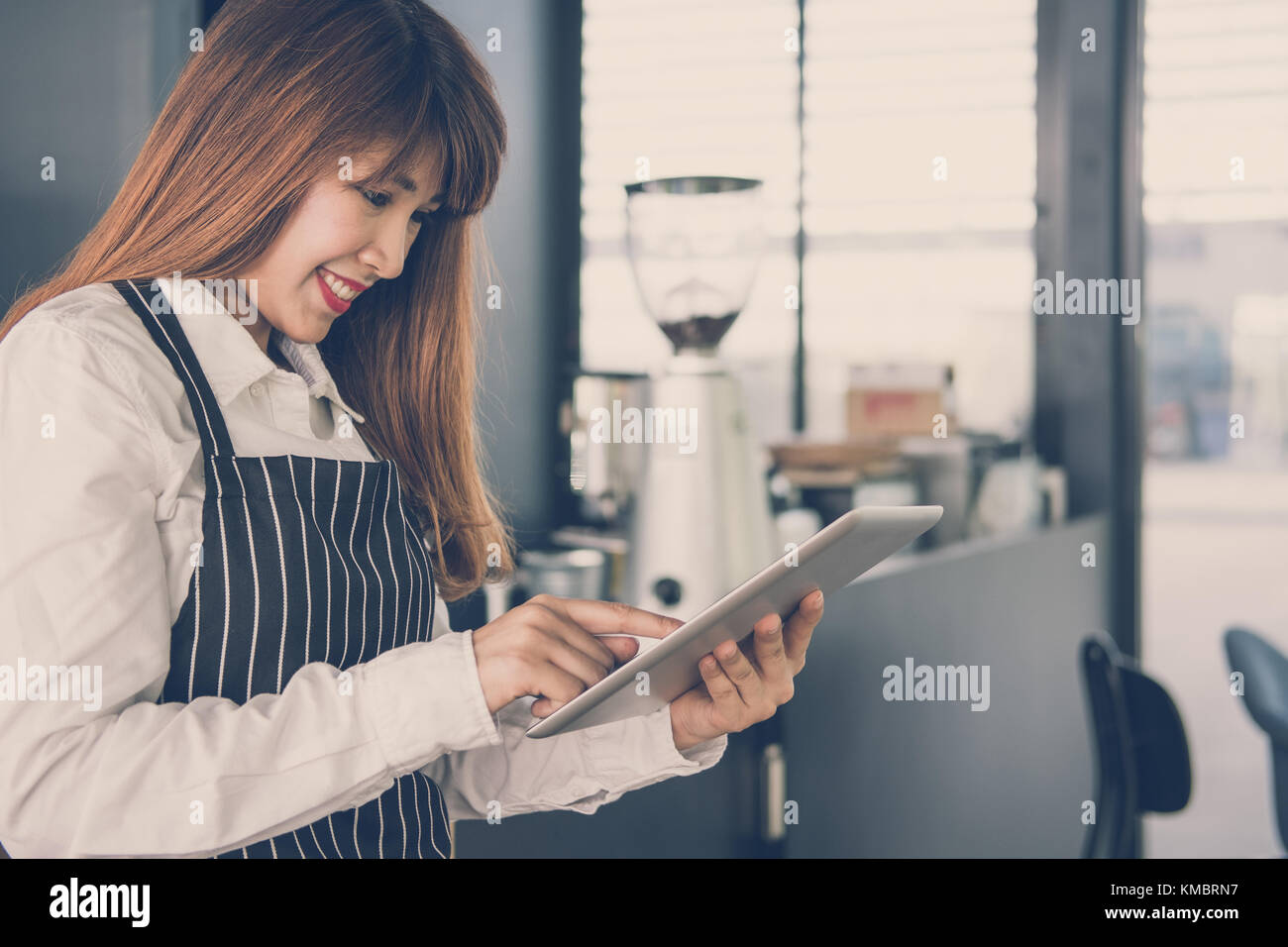 Propriétaire de petite entreprise holding tablet in coffee shop. asian female barista de porter un tablier à l'aide au touchpad dans bar cafe. service alimentaire, restaur Banque D'Images