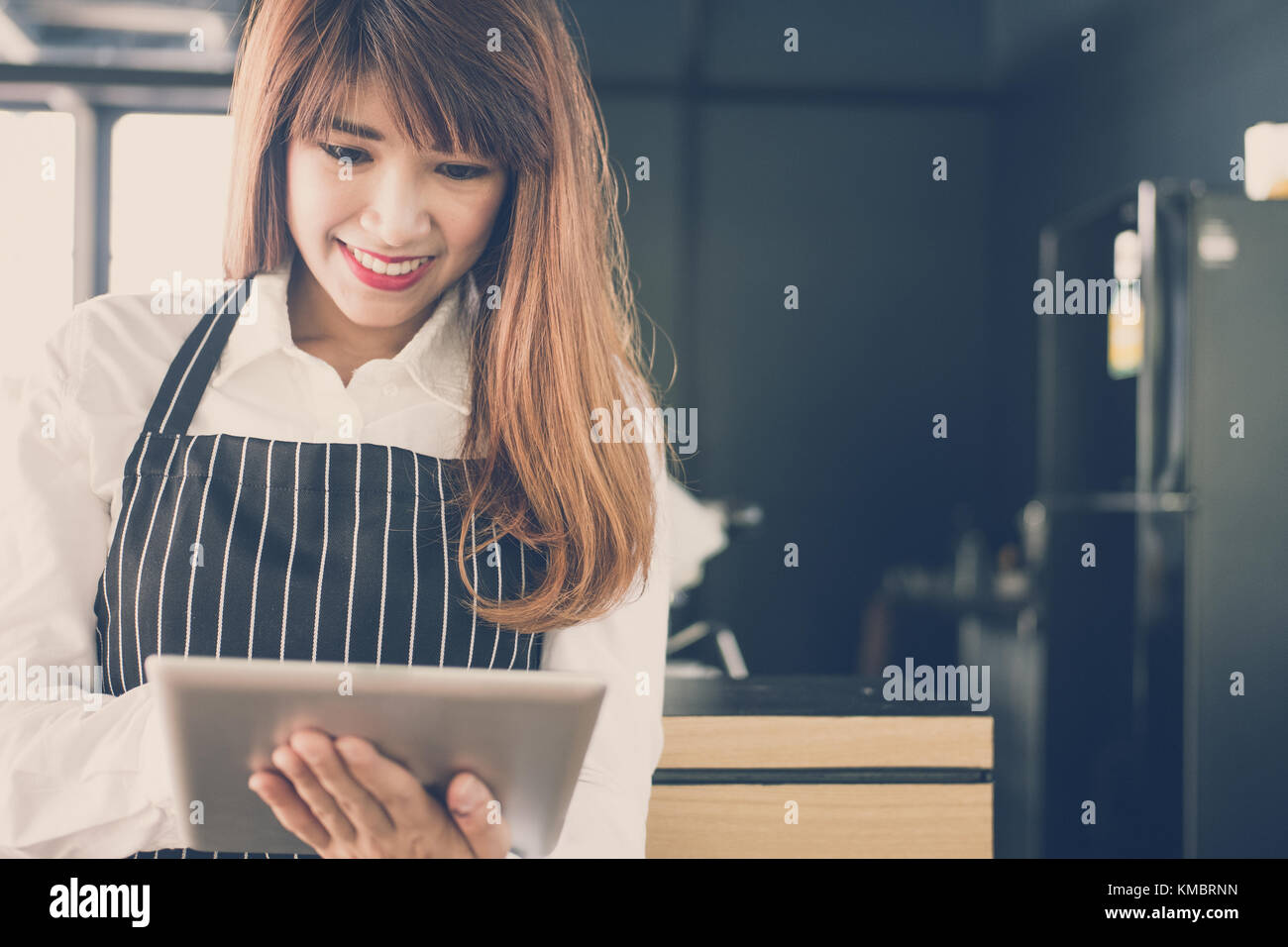 Propriétaire de petite entreprise holding tablet in coffee shop. asian female barista de porter un tablier à l'aide au touchpad dans bar cafe. service alimentaire, restaur Banque D'Images