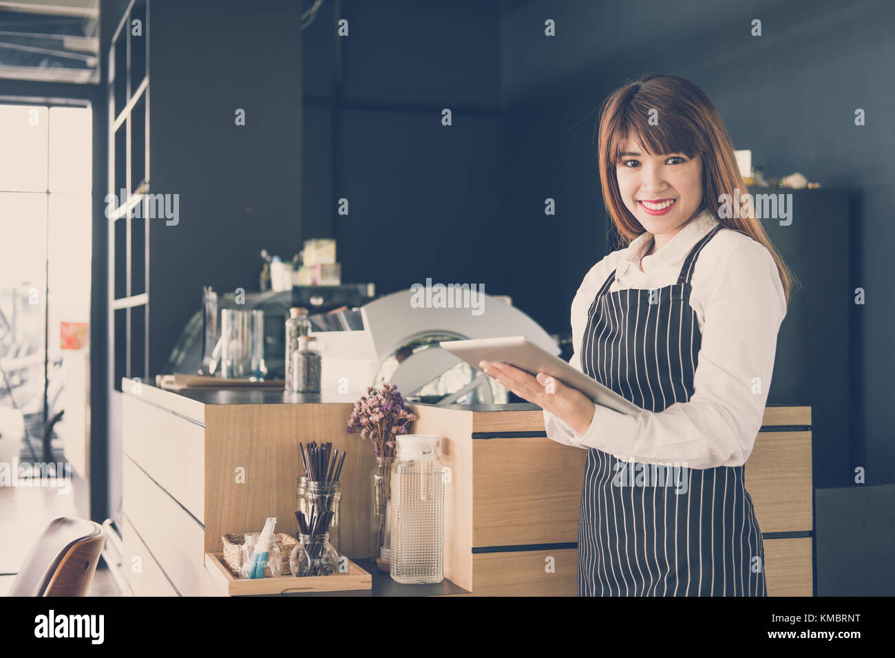 Propriétaire de petite entreprise holding tablet in coffee shop. asian female barista de porter un tablier à l'aide au touchpad dans bar cafe. service alimentaire, restaur Banque D'Images