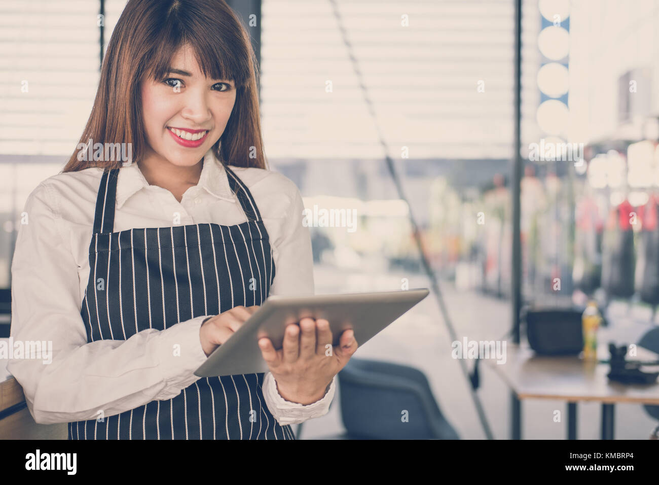 Propriétaire de petite entreprise holding tablet in coffee shop. asian female barista de porter un tablier à l'aide au touchpad dans bar cafe. service alimentaire, restaur Banque D'Images