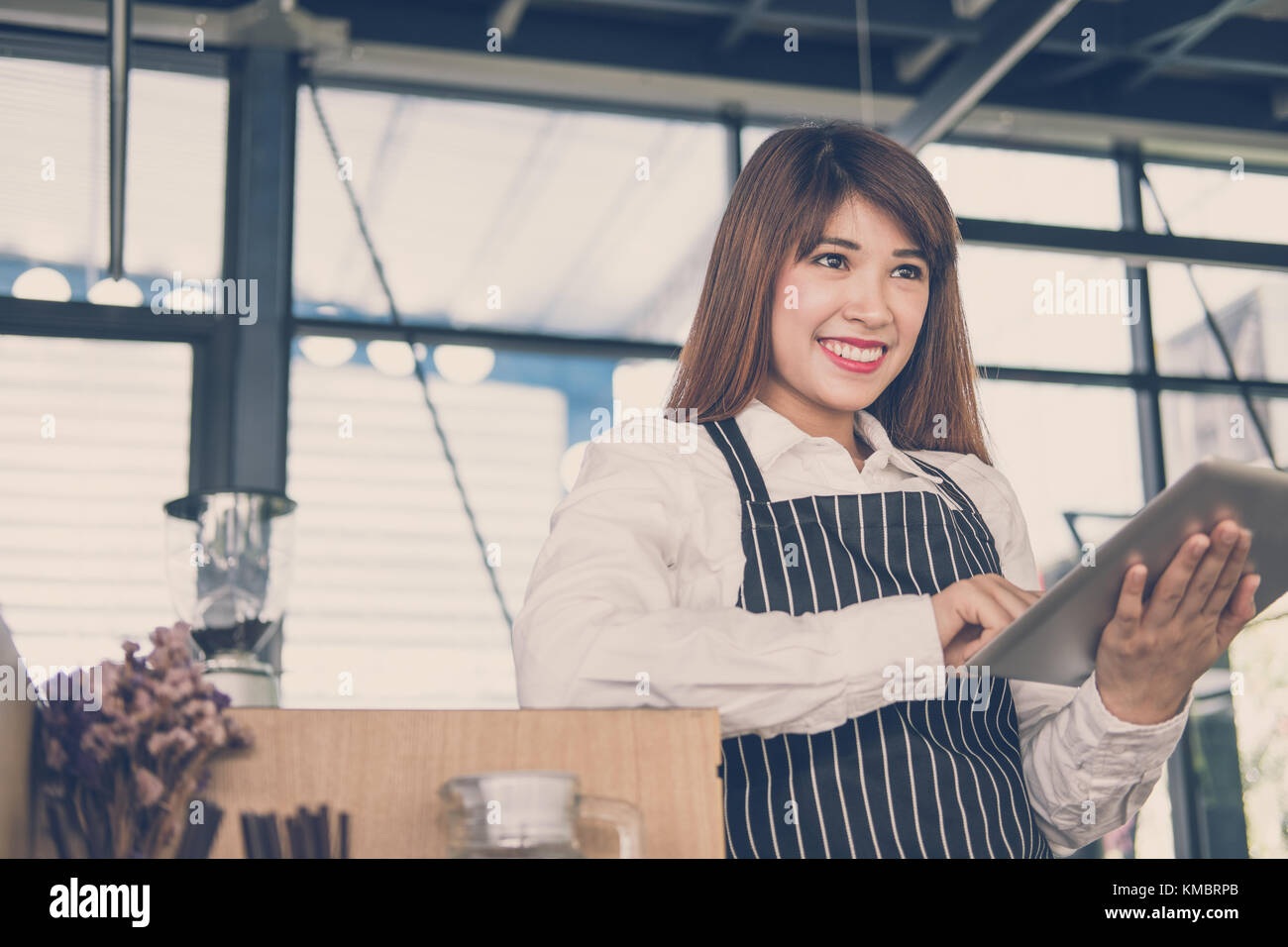 Propriétaire de petite entreprise holding tablet in coffee shop. asian female barista de porter un tablier à l'aide au touchpad dans bar cafe. service alimentaire, restaur Banque D'Images