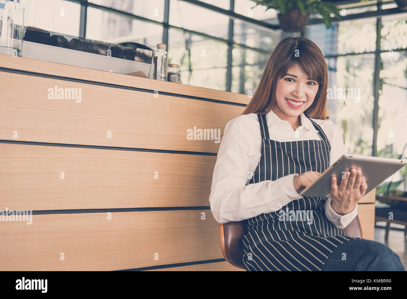 Propriétaire de petite entreprise holding tablet in coffee shop. asian female barista de porter un tablier à l'aide au touchpad dans bar cafe. service alimentaire, restaur Banque D'Images
