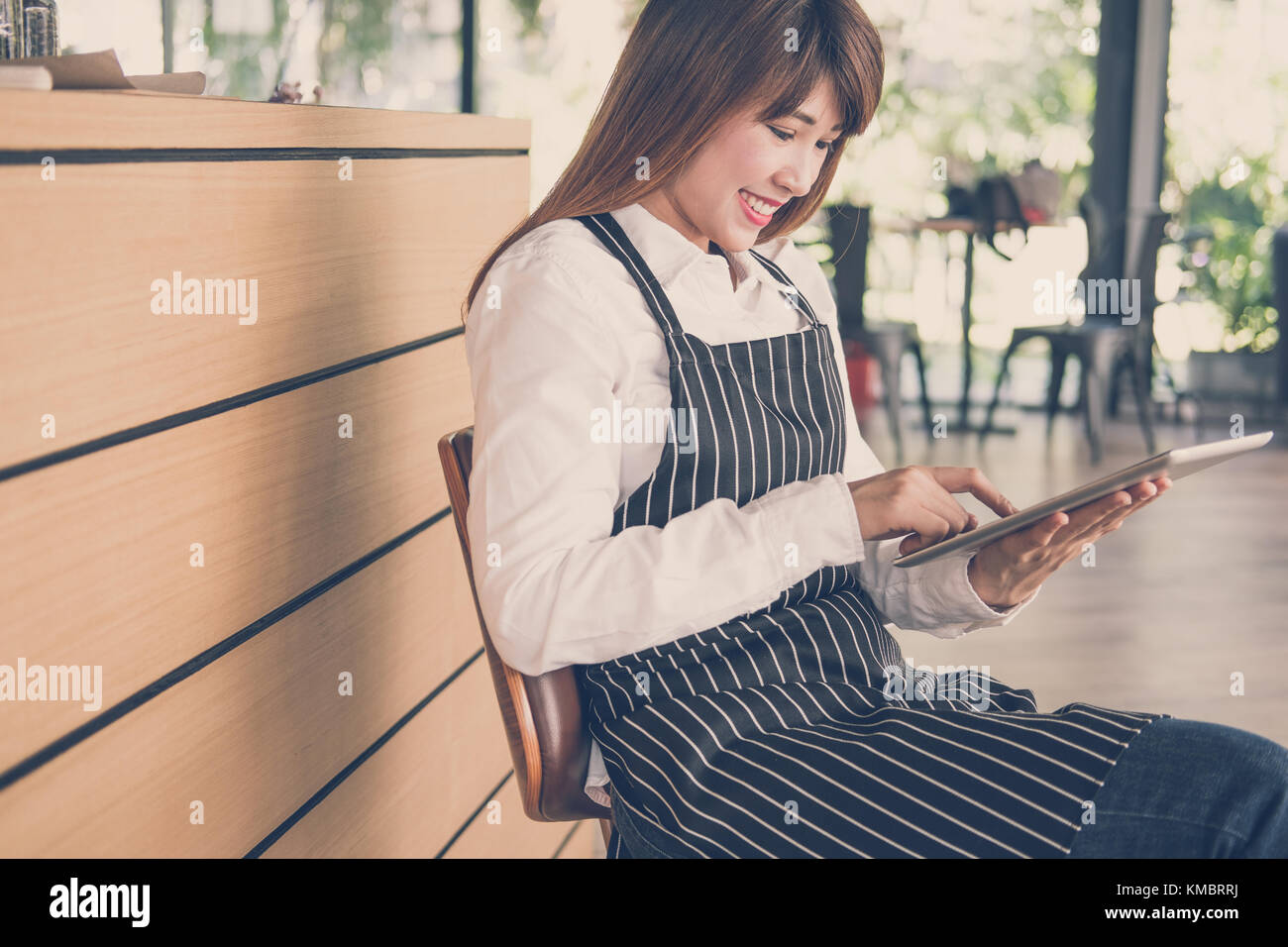 Propriétaire de petite entreprise holding tablet in coffee shop. asian female barista de porter un tablier à l'aide au touchpad dans bar cafe. service alimentaire, restaur Banque D'Images