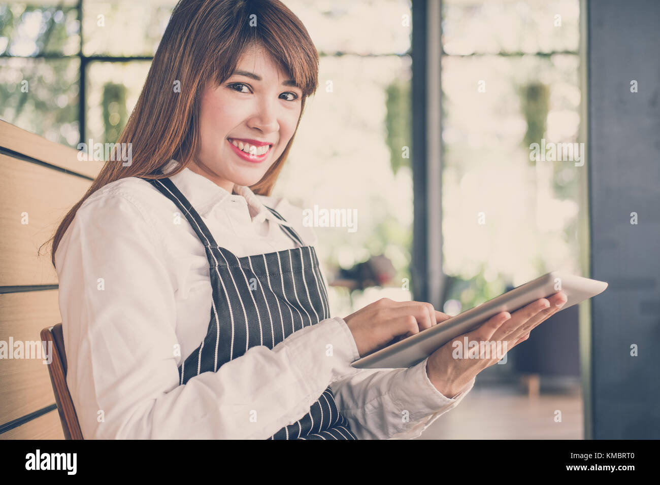 Propriétaire de petite entreprise holding tablet in coffee shop. asian female barista de porter un tablier à l'aide au touchpad dans bar cafe. service alimentaire, restaur Banque D'Images