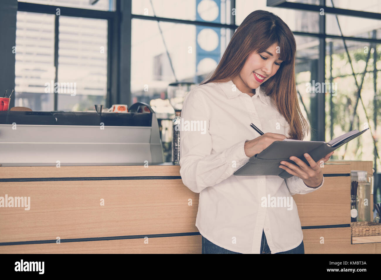 Propriétaire de petite entreprise holding notebook au comptoir à café. asian female barista note par écrit au barreau en cafe. food service, concept de restaurant. Banque D'Images