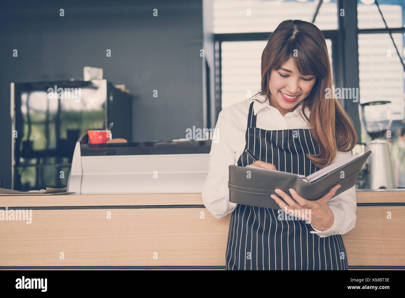 Propriétaire de petite entreprise holding notebook au comptoir à café. asian female barista portant un tablier écrit la note à la bar dans le café. Les services alimentaires, restaur Banque D'Images