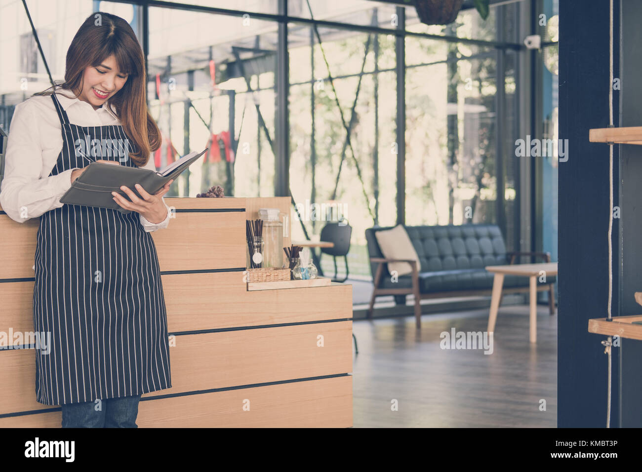 Propriétaire de petite entreprise holding notebook au comptoir à café. asian female barista portant un tablier écrit la note à la bar dans le café. Les services alimentaires, restaur Banque D'Images