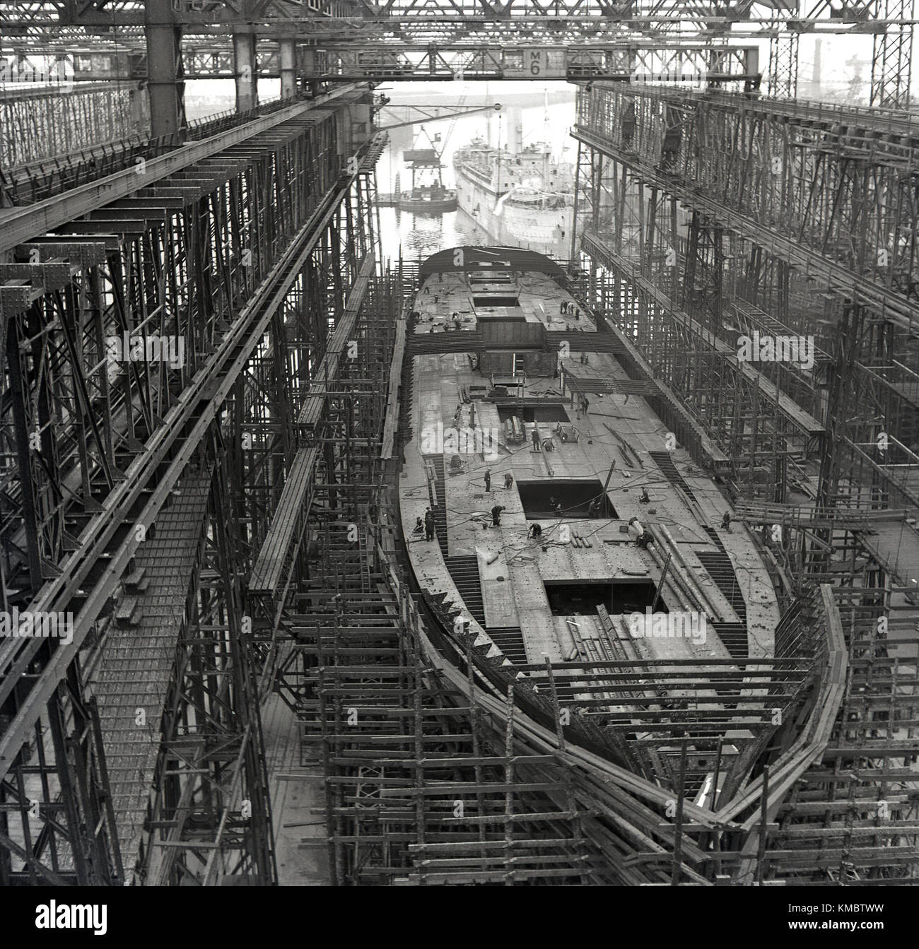 Années 1950, tableau historique d'un navire en construction dans une cale sèche sous le portique Arrol au célèbre chantier naval Harland and Wolff, où le Titanic et autres grands navires de classe olympique ont été construites, Belfast, Irlande du Nord. Banque D'Images
