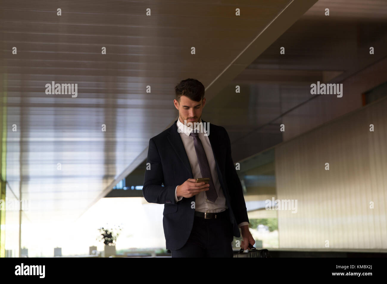 Businessman texting with smart phone in office lobby Banque D'Images