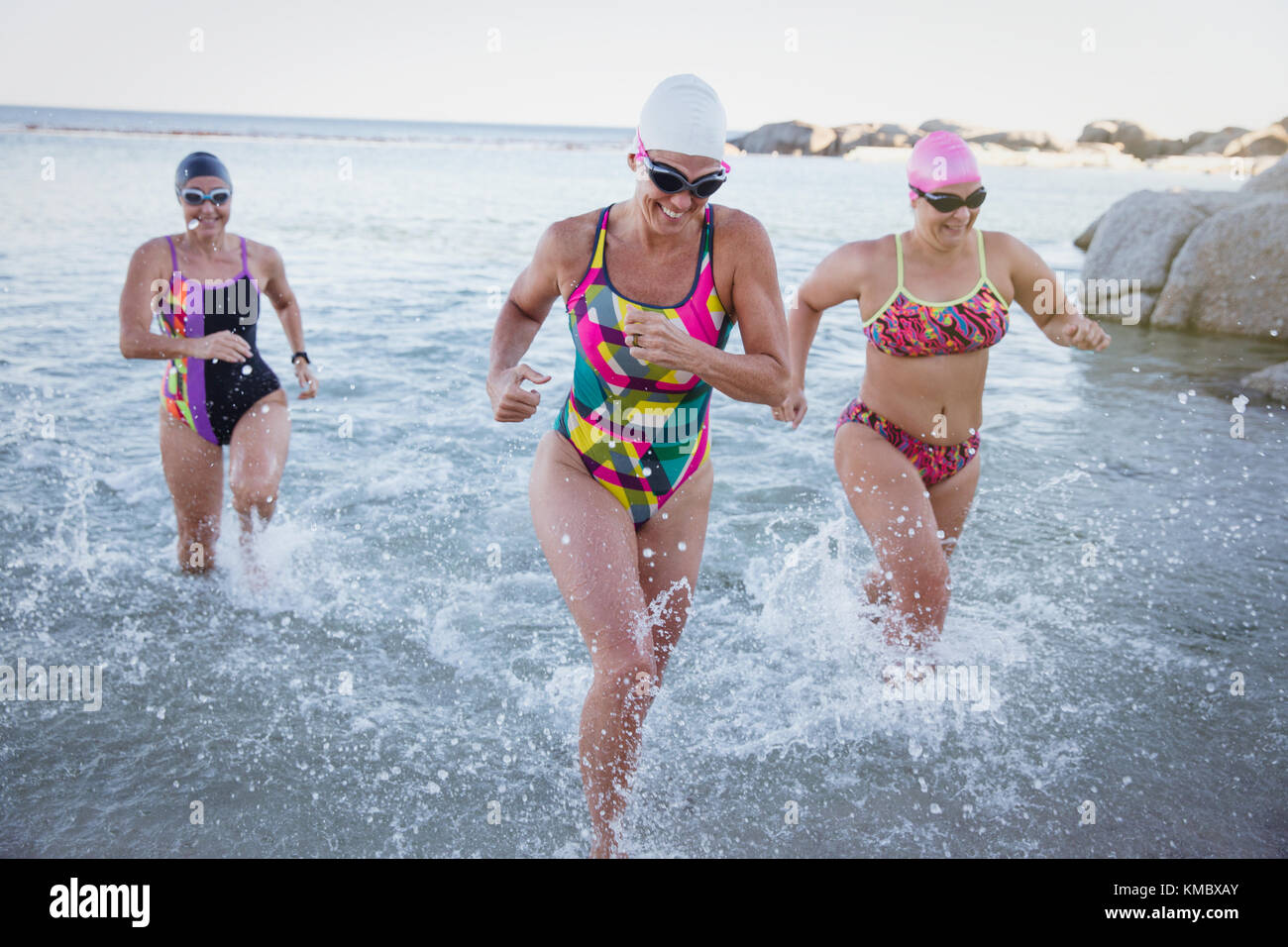 Les nageurs en eau libre féminin en marche et de s'éclabousser dans océan surf Banque D'Images