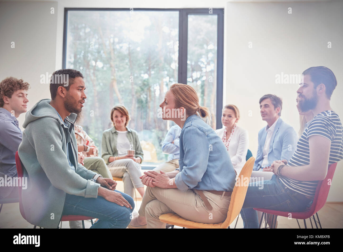 Groupe regardant homme et femme parlant face à face dans la séance de thérapie de groupe Banque D'Images