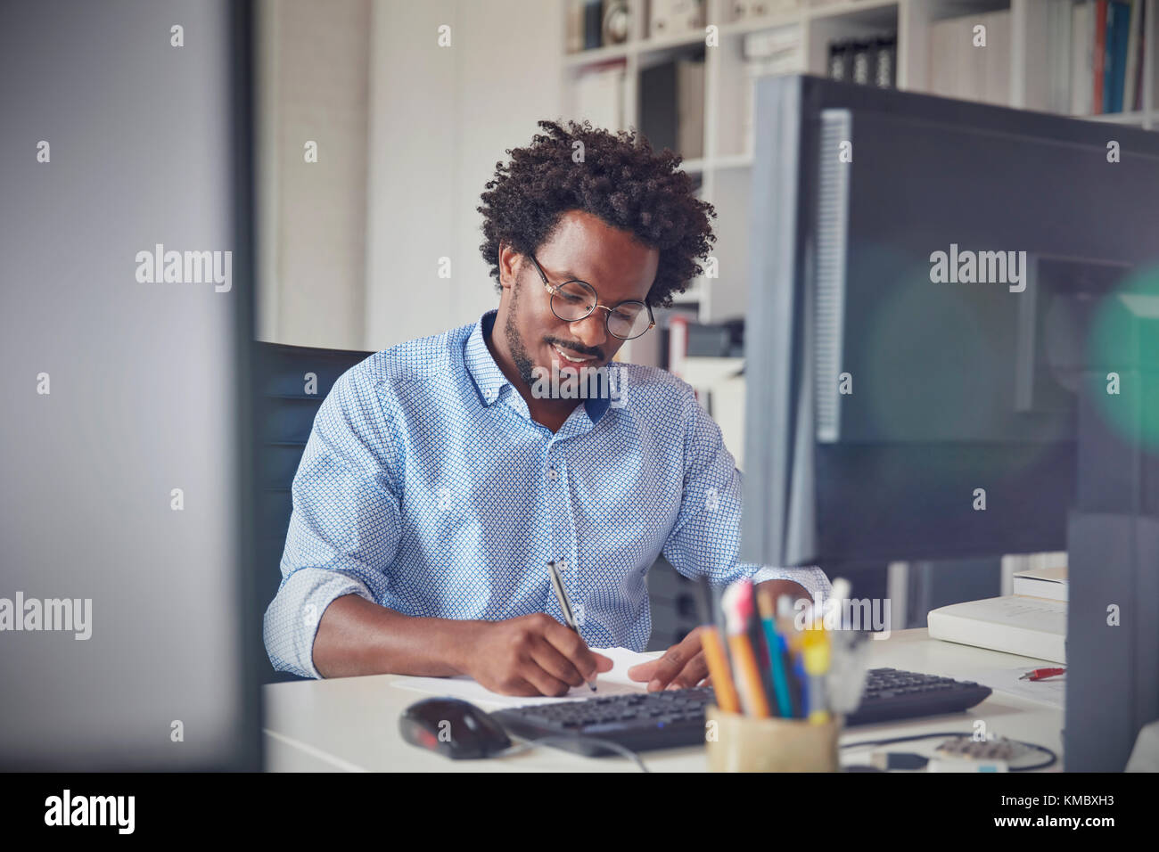 Homme d'affaires prenant des notes à l'ordinateur dans le bureau Banque D'Images