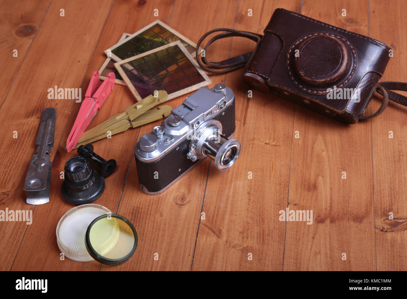 Vintage old photo-camera, étui en cuir et autres accessoires photo sur fond de bois. Banque D'Images