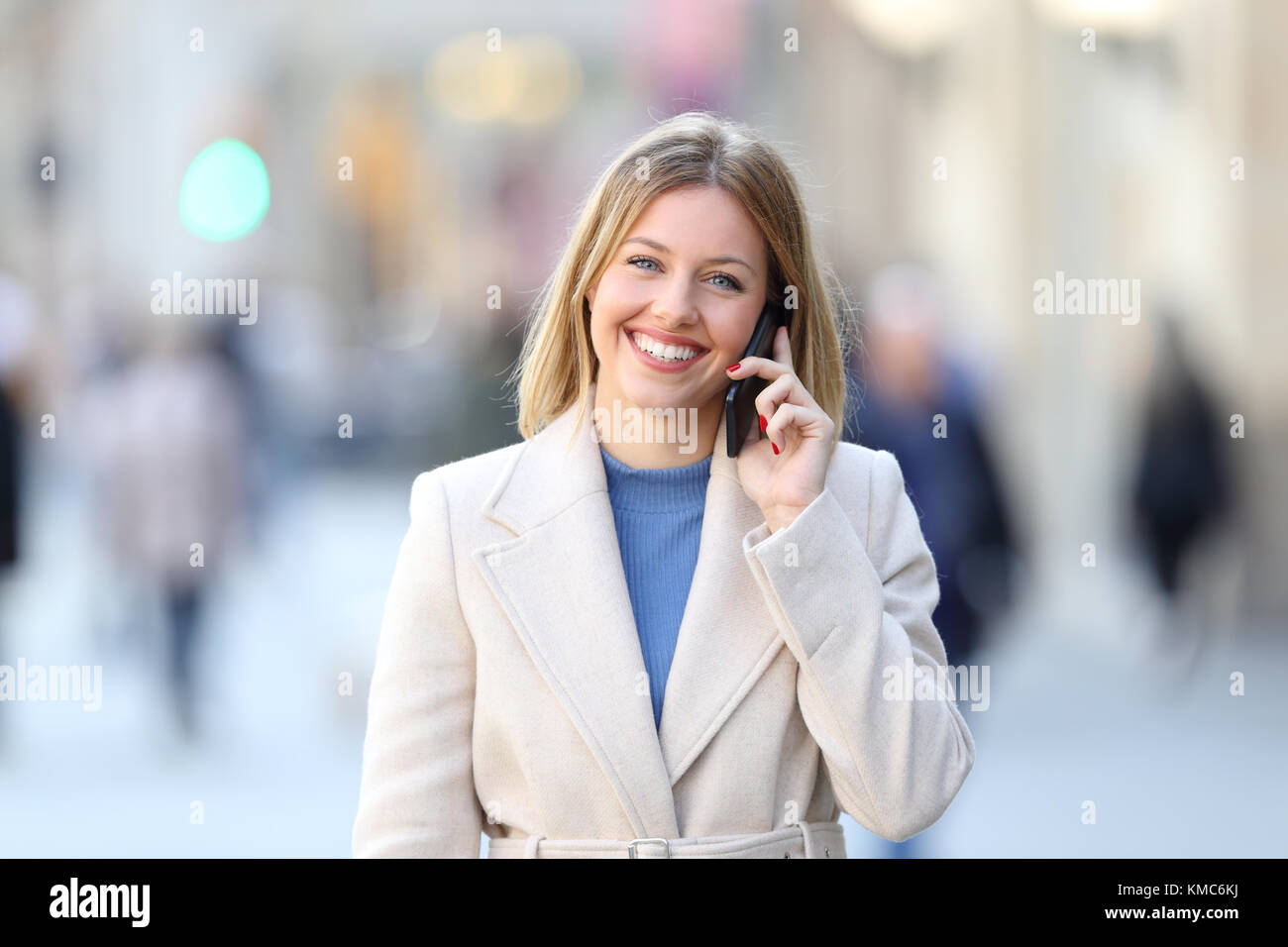 Vue avant portrait of a happy dame appelant sur le téléphone et à la caméra à dans la rue en hiver Banque D'Images