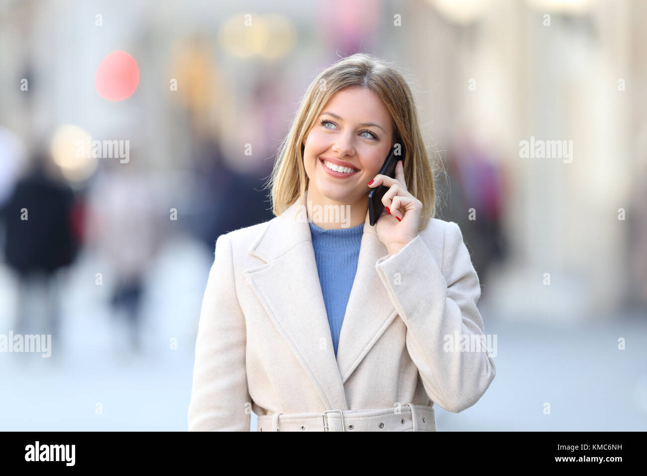 Vue avant, portrait d'une femme portant un manteau blanc appelant sur le téléphone et à côté à dans la rue en hiver Banque D'Images