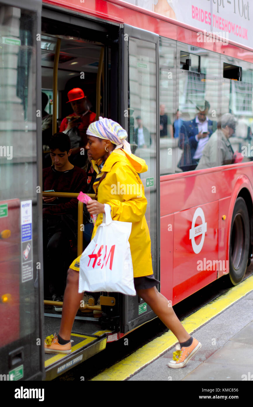 Femme avec panier d'aller dans un bus rouge, London, England, UK Banque D'Images