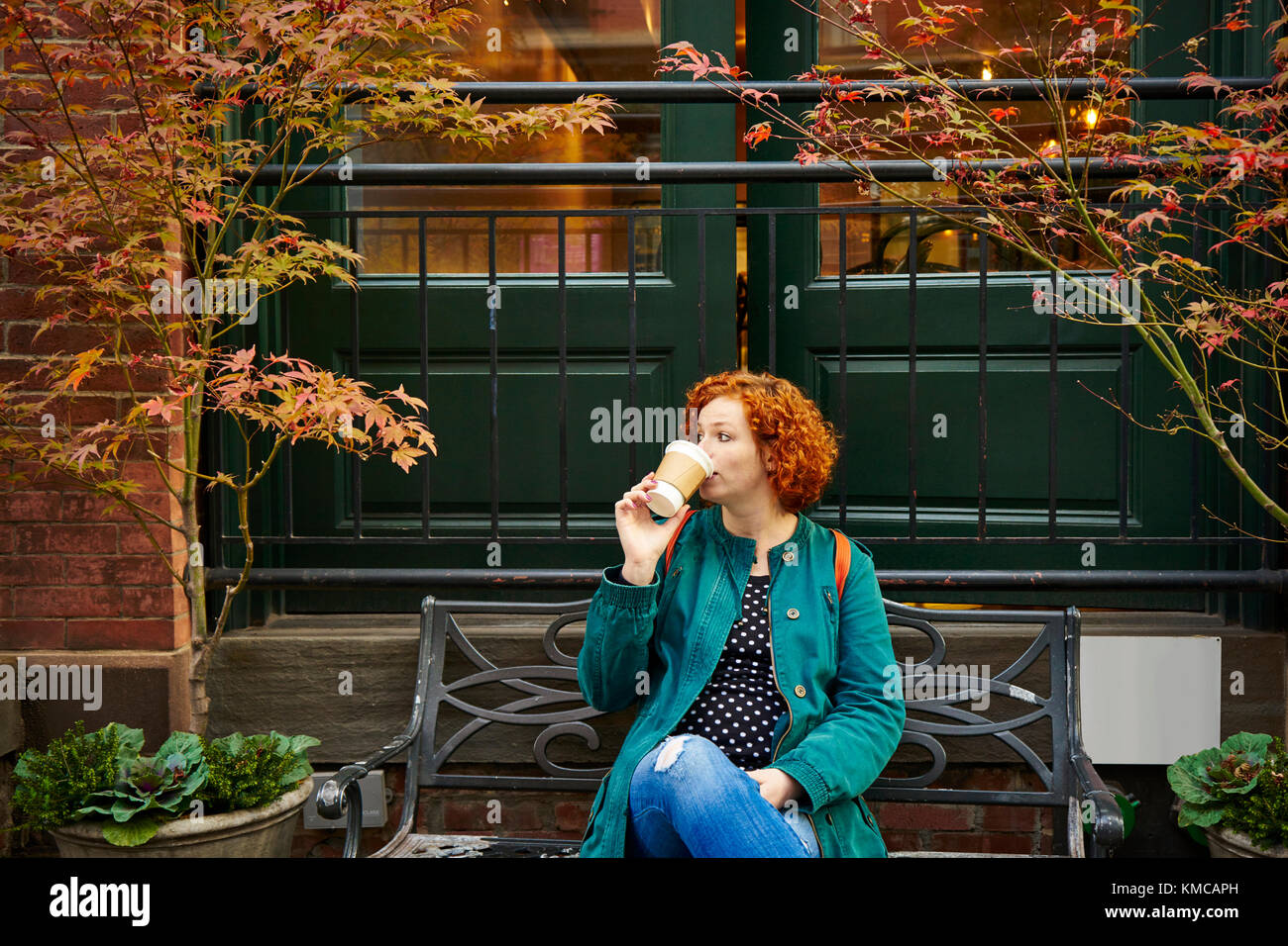 Jeune rousse Femme buvant du café sur le banc en face de café très agréable. Banque D'Images