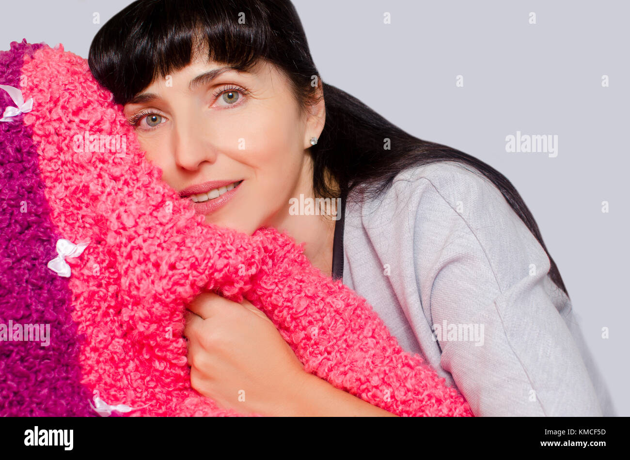 Une belle femme avec un léger sourire s'accroche à son plaid chaud pour garder au chaud Banque D'Images