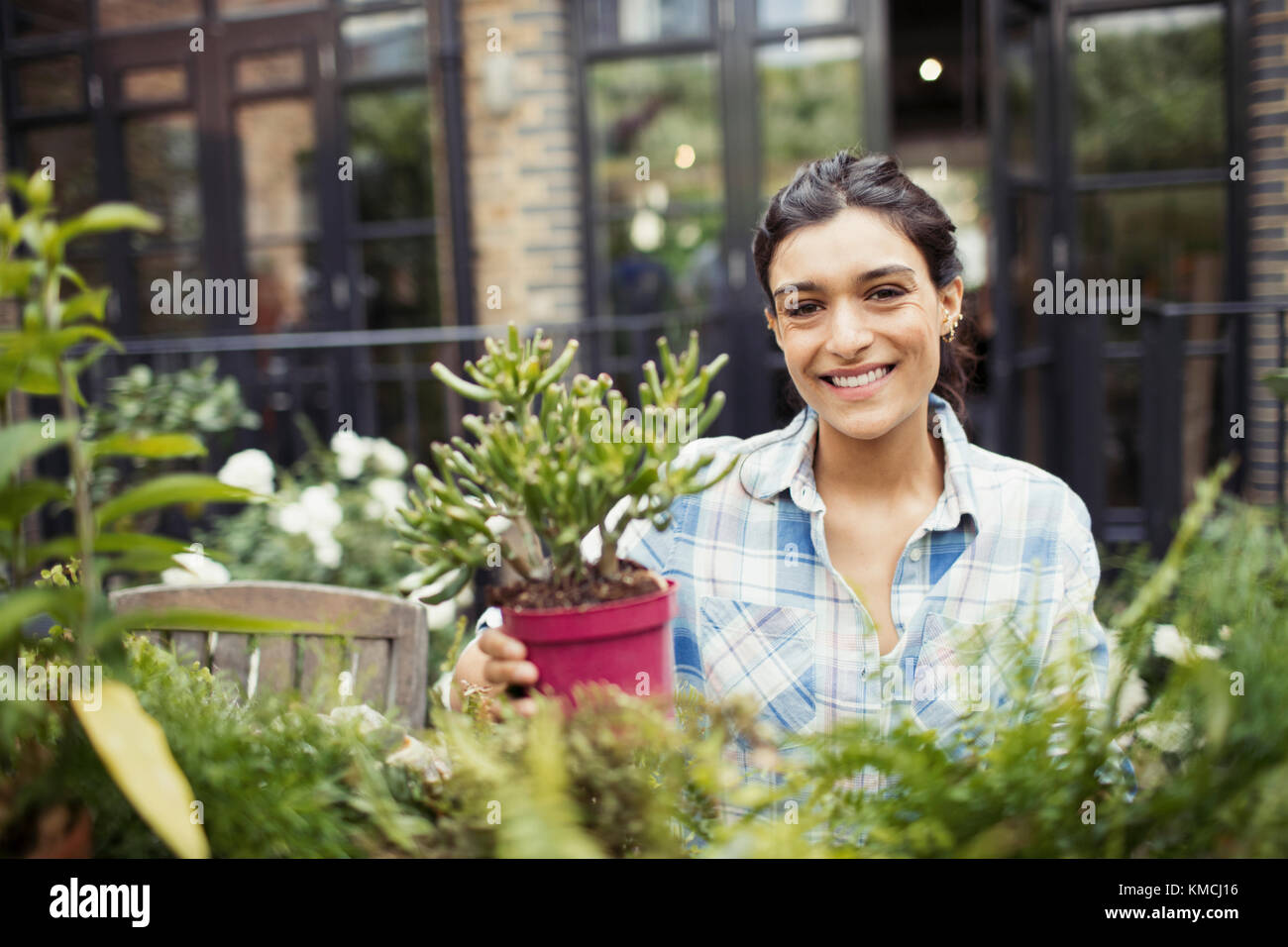 Portrait souriant jeune femme jardinage avec plantes en pot sur le patio Banque D'Images