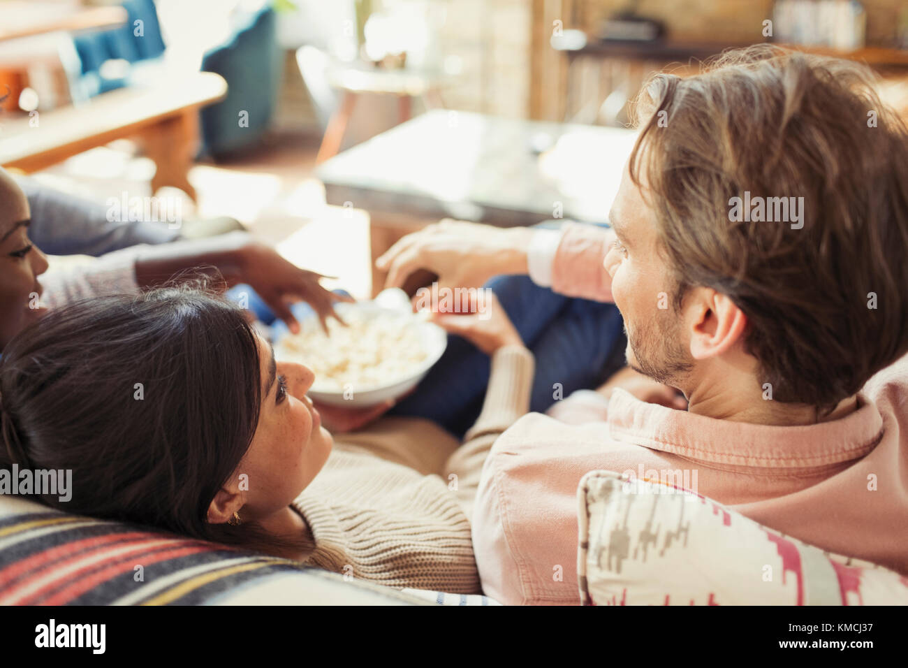 Amis regardant la télévision et partageant du pop-corn dans le salon Banque D'Images