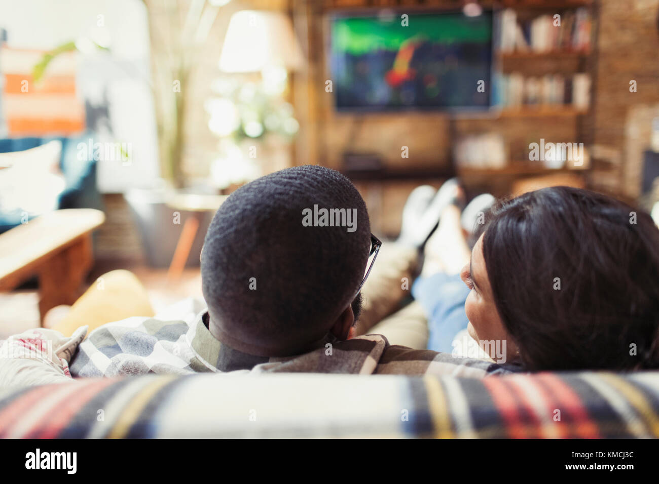 Un jeune couple se détendant, regardant la télévision sur le canapé du salon Banque D'Images