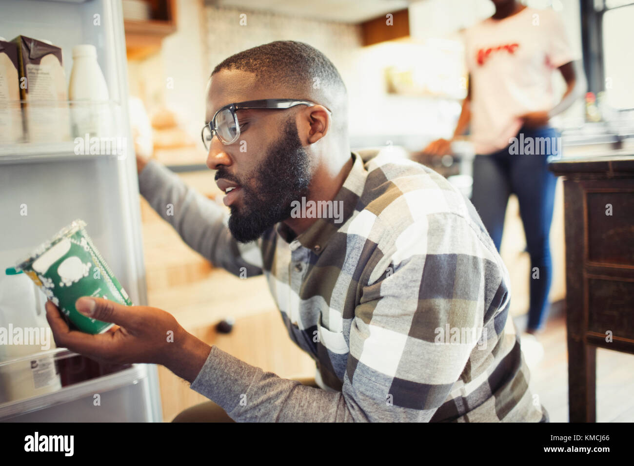 Jeune homme lisant l'étiquette sur le contenant au réfrigérateur Banque D'Images