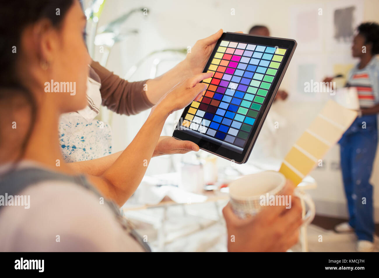 Une jeune femme boit du café et regarde les échantillons de peinture numérique tablette numérique Banque D'Images