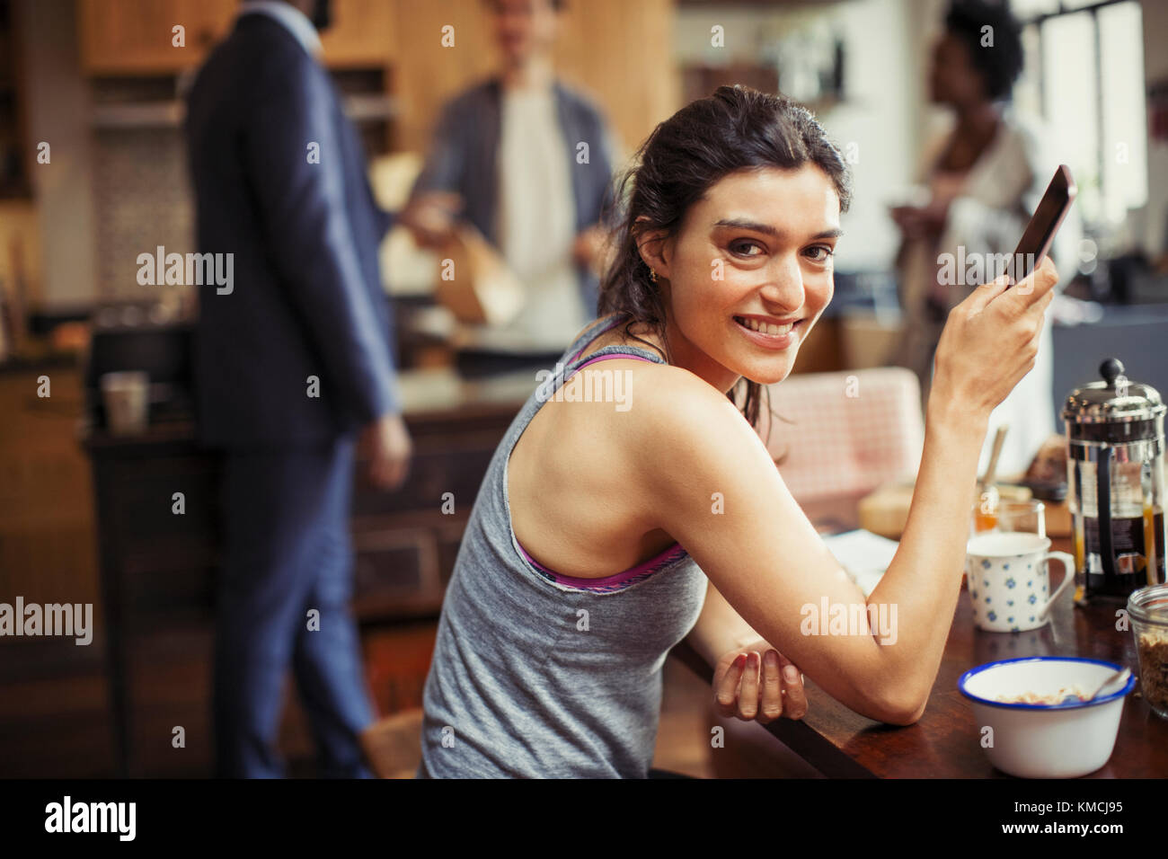 Portrait souriant jeune femme textant avec un smartphone au petit déjeuner tableau Banque D'Images