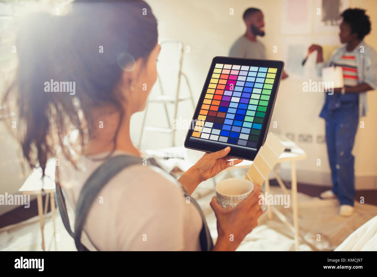Jeune femme avec tablette numérique regardant les nuances de peinture numérique, peinture salon Banque D'Images