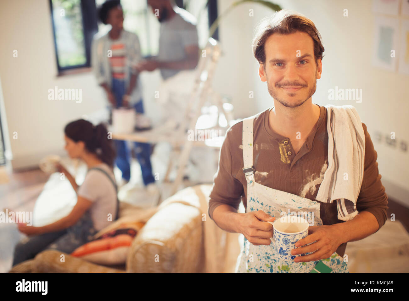 Portrait souriant homme buvant du café et peinture salon Banque D'Images