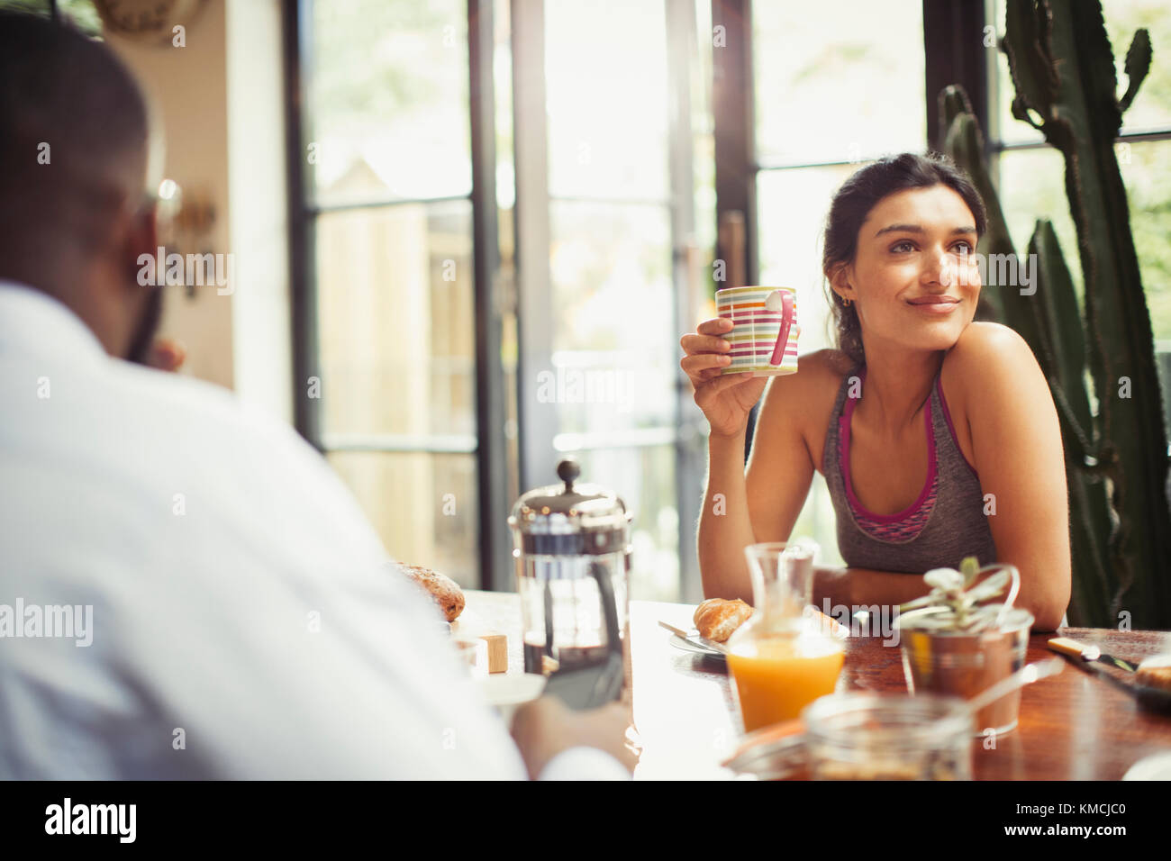 Femme souriante buvant du café à la table du petit déjeuner Banque D'Images