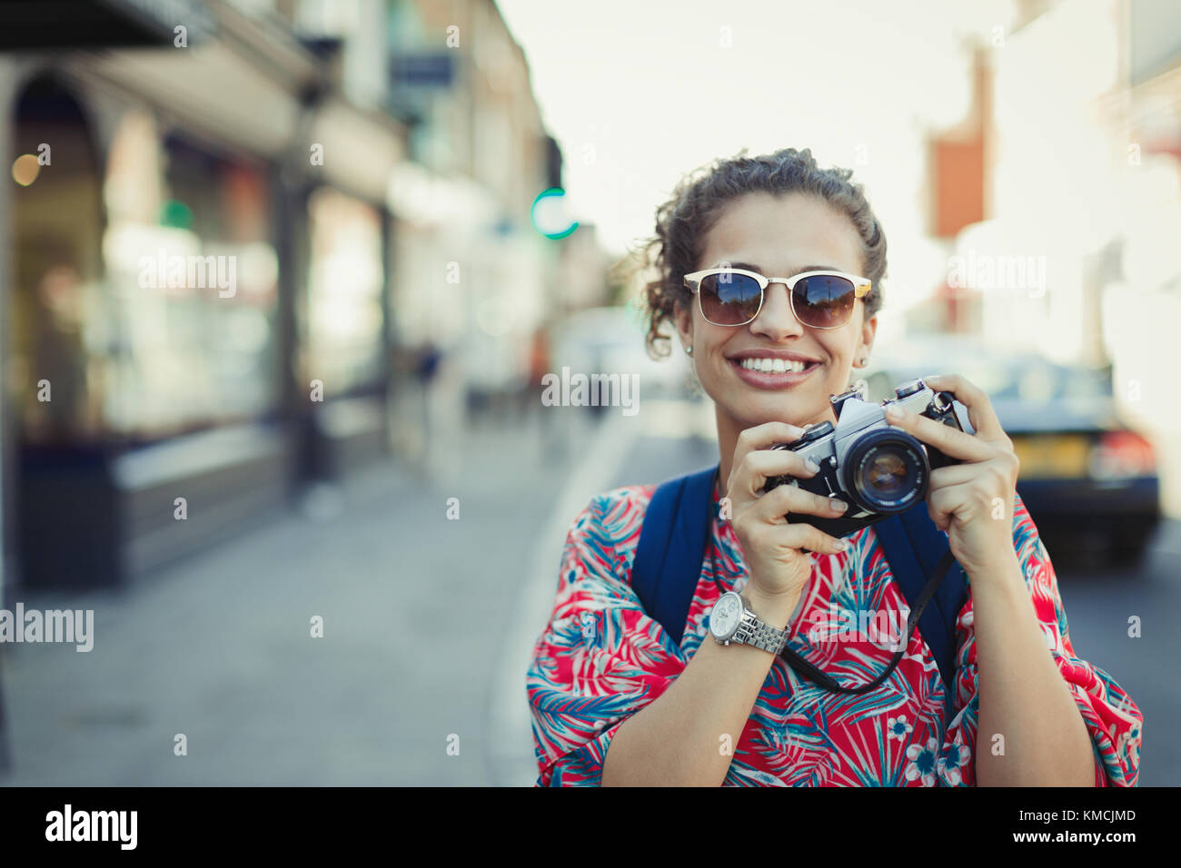 Portrait souriant jeune femme touriste dans des lunettes de soleil photographie avec un appareil photo sur la rue urbaine Banque D'Images