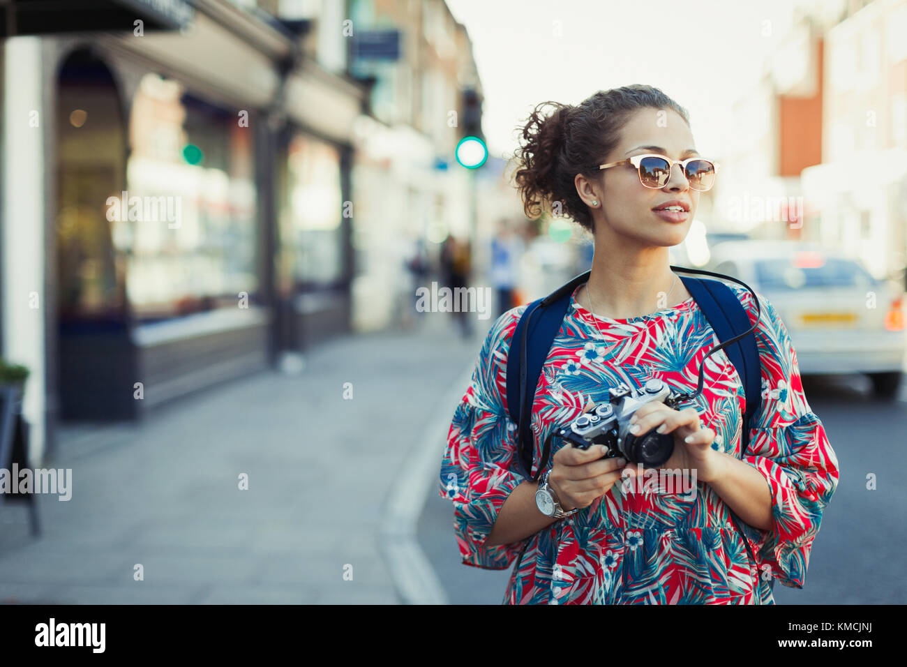 Jeune touriste femelle dans des lunettes de soleil avec appareil photo dans la rue urbaine Banque D'Images