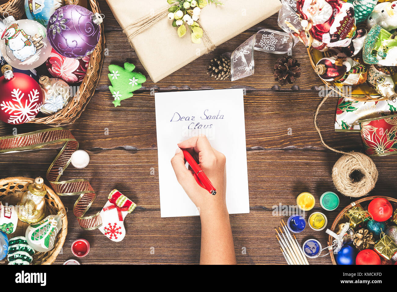 Fond de Noël avec des décorations, boules, cadeaux et jouets sur planche de bois. Fille main écrit une lettre Cher Père Noël. Belle idée noël fo Banque D'Images