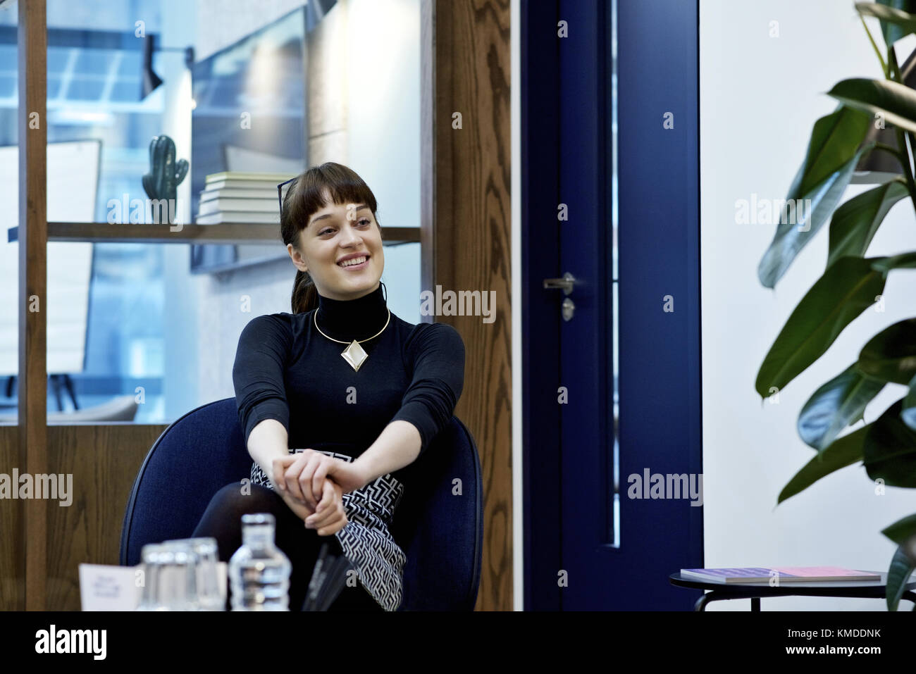 Caucasian businesswoman smiling and gesturing at collègues hors-champ dans un bureau contemporain Banque D'Images