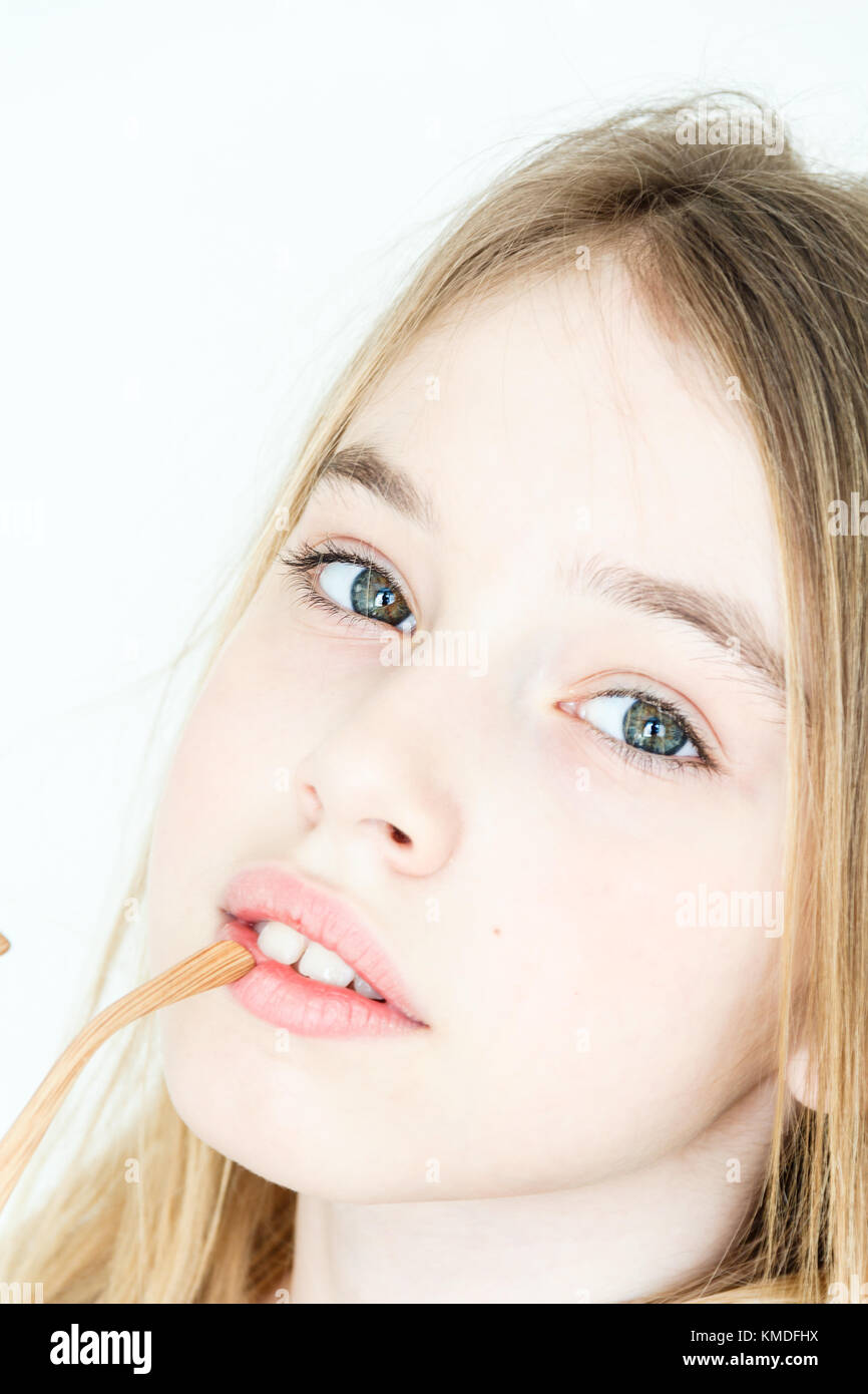 Jolie fille 11 ans avec de longs cheveux blonds et les yeux verts sur fond blanc Banque D'Images