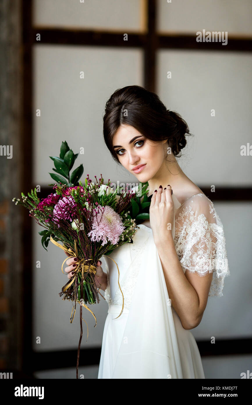 Belle robe de mariée assis sur une chaise à l'intérieur dans dark studio intérieur comme à la maison. Banque D'Images